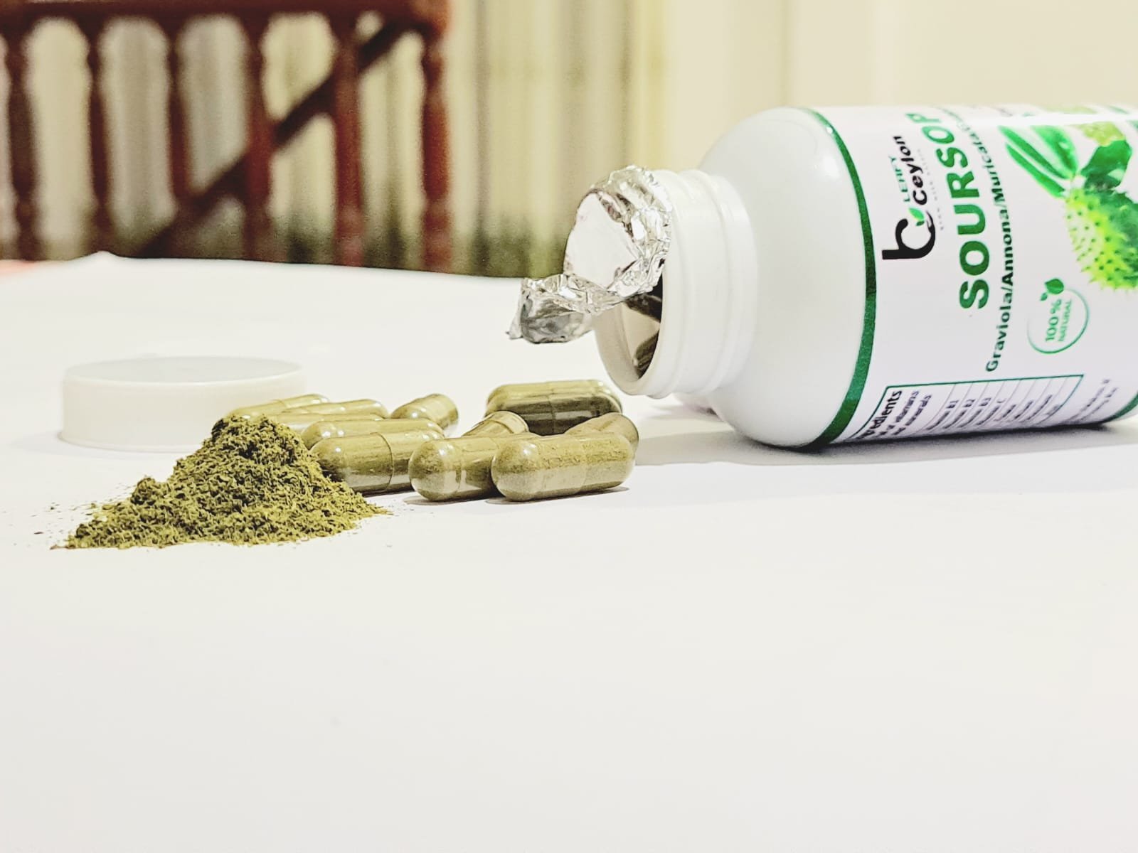 Soursop capsule bottle on its side with capsules and green powder
