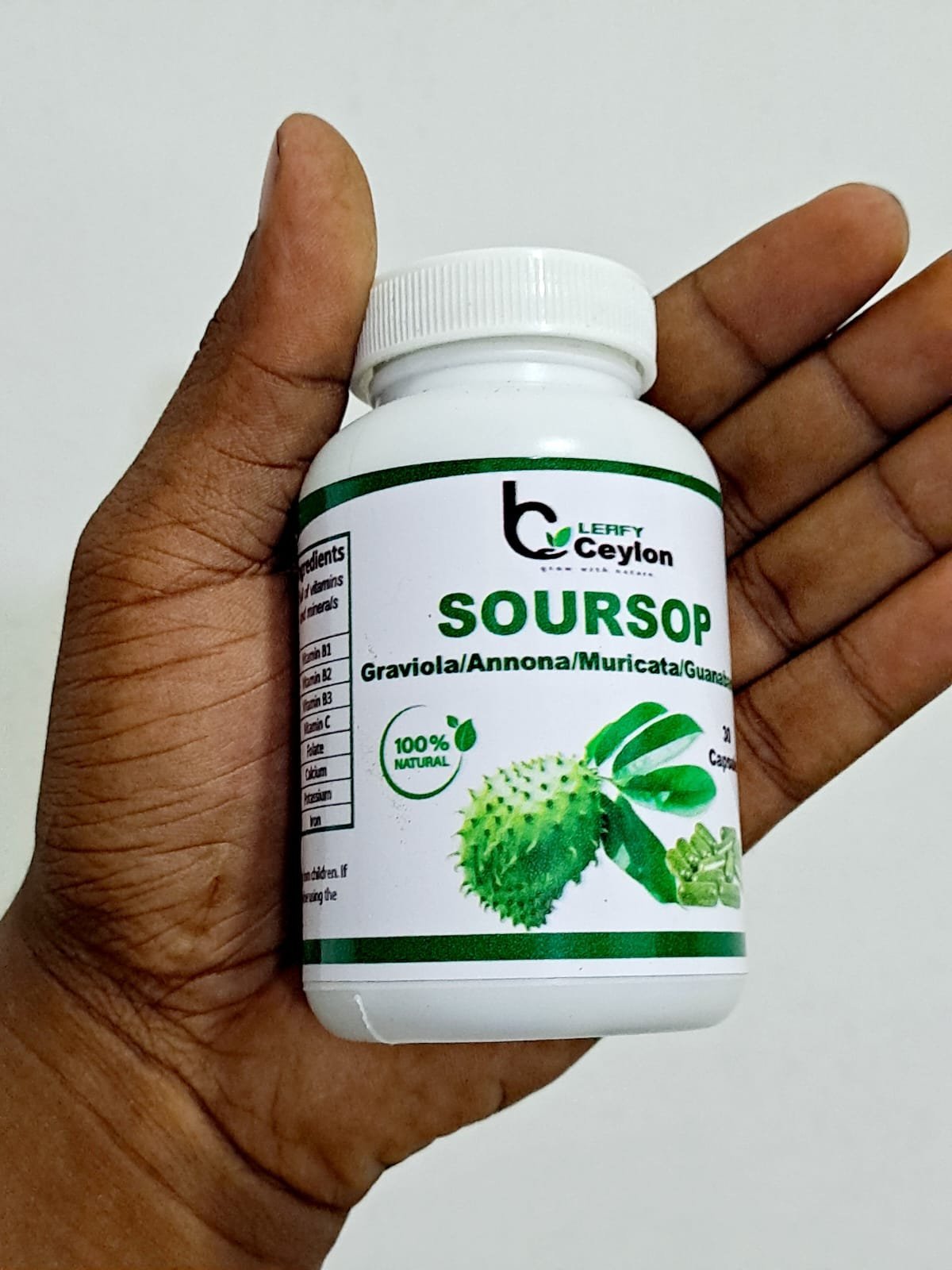 A hand holding a Leafy Ceylon soursop capsule bottle